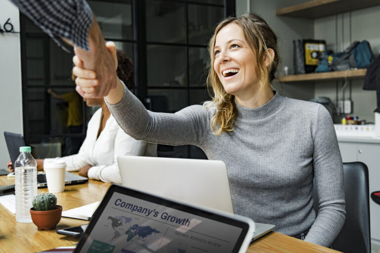 Business people shaking hands demonstrating the collaboration needs to see growth in KPIs for Sales Marketing Alignment.